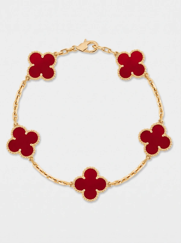 Gold-tone bracelet with five red clover-shaped motifs on a light background